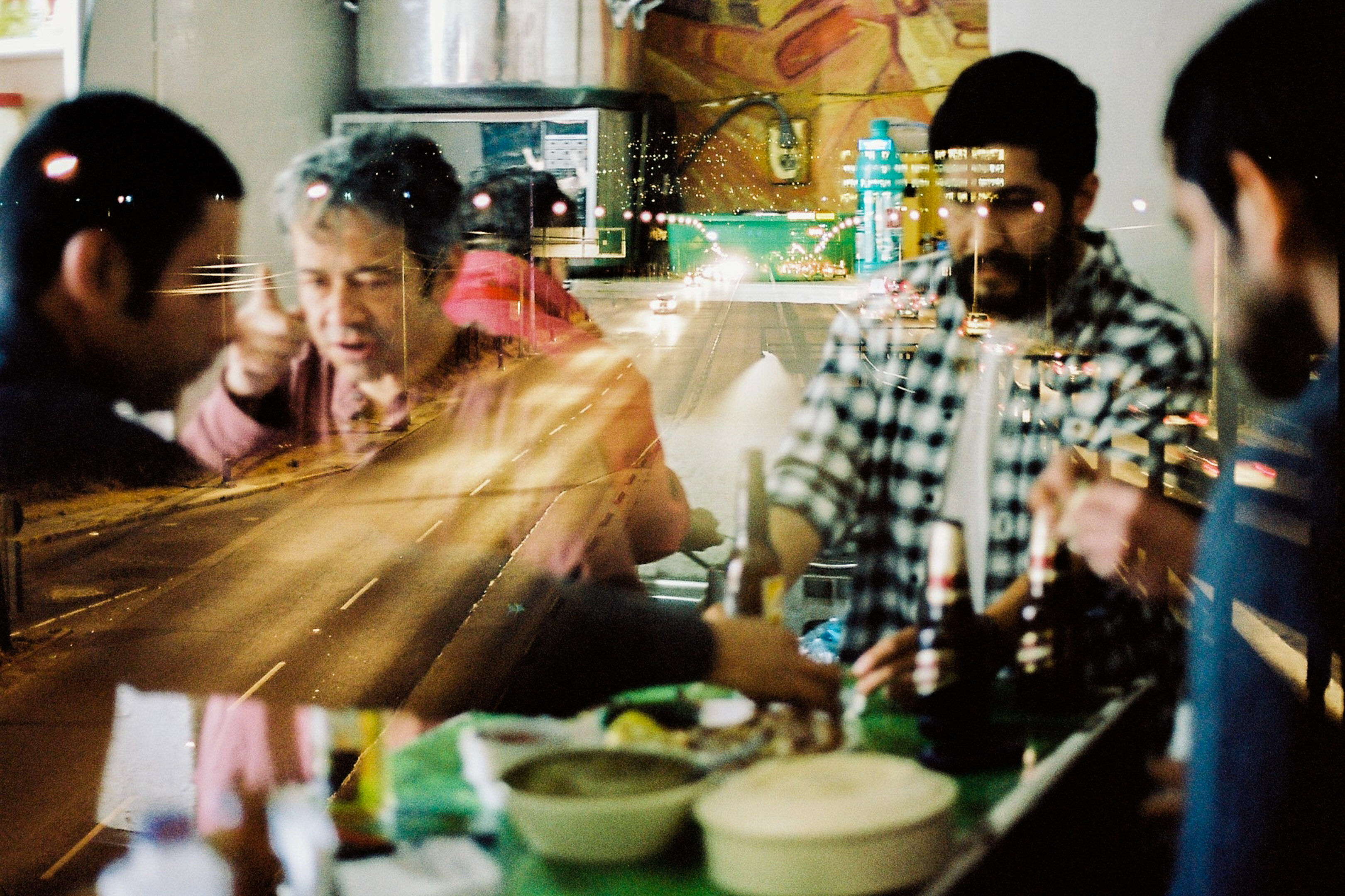 Double exposed image of 4 man drinking and eating inside a cantina and an overlay of a highway in the night