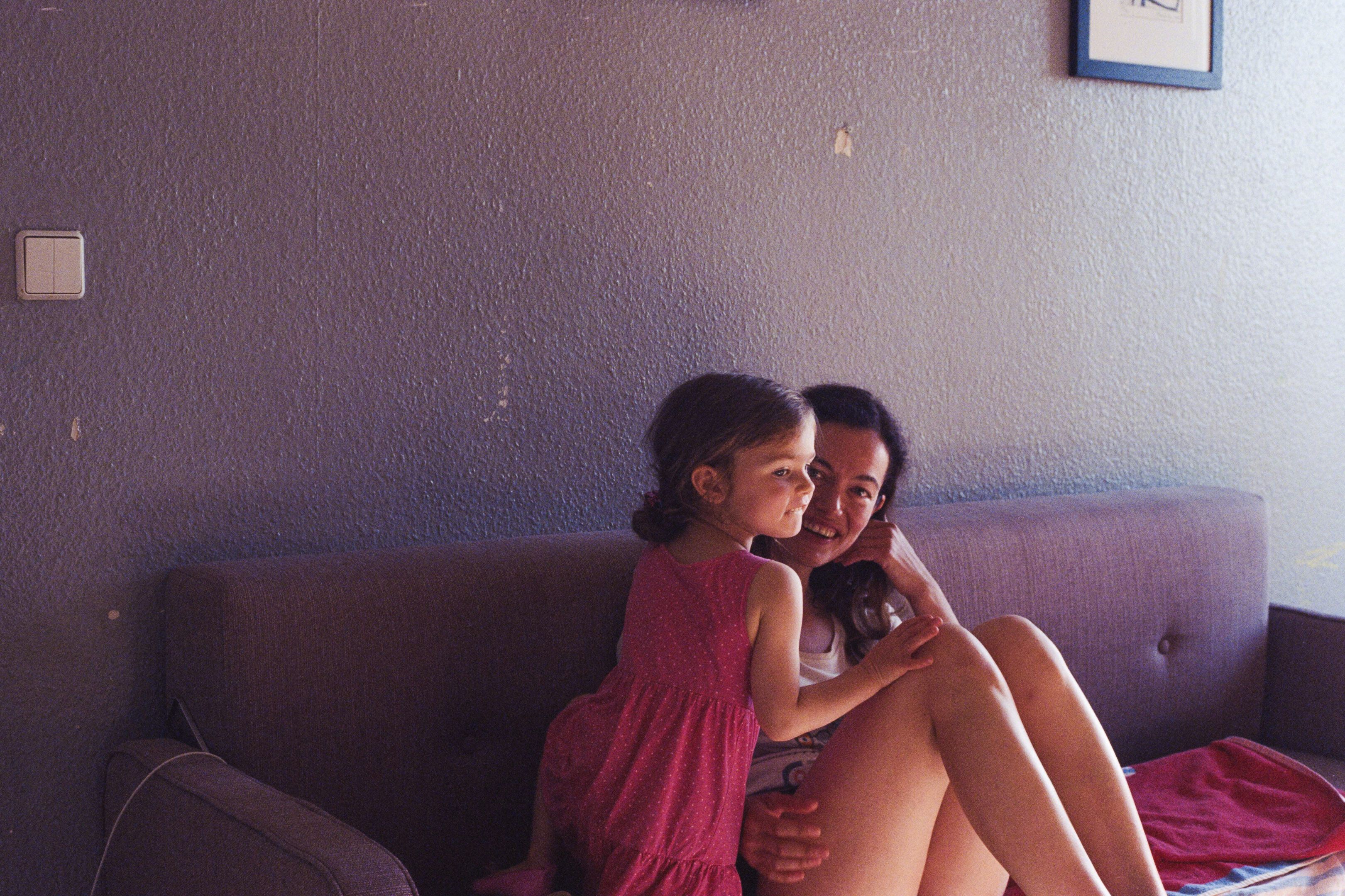 Mother and daughter at home sitting on the couch in the summer