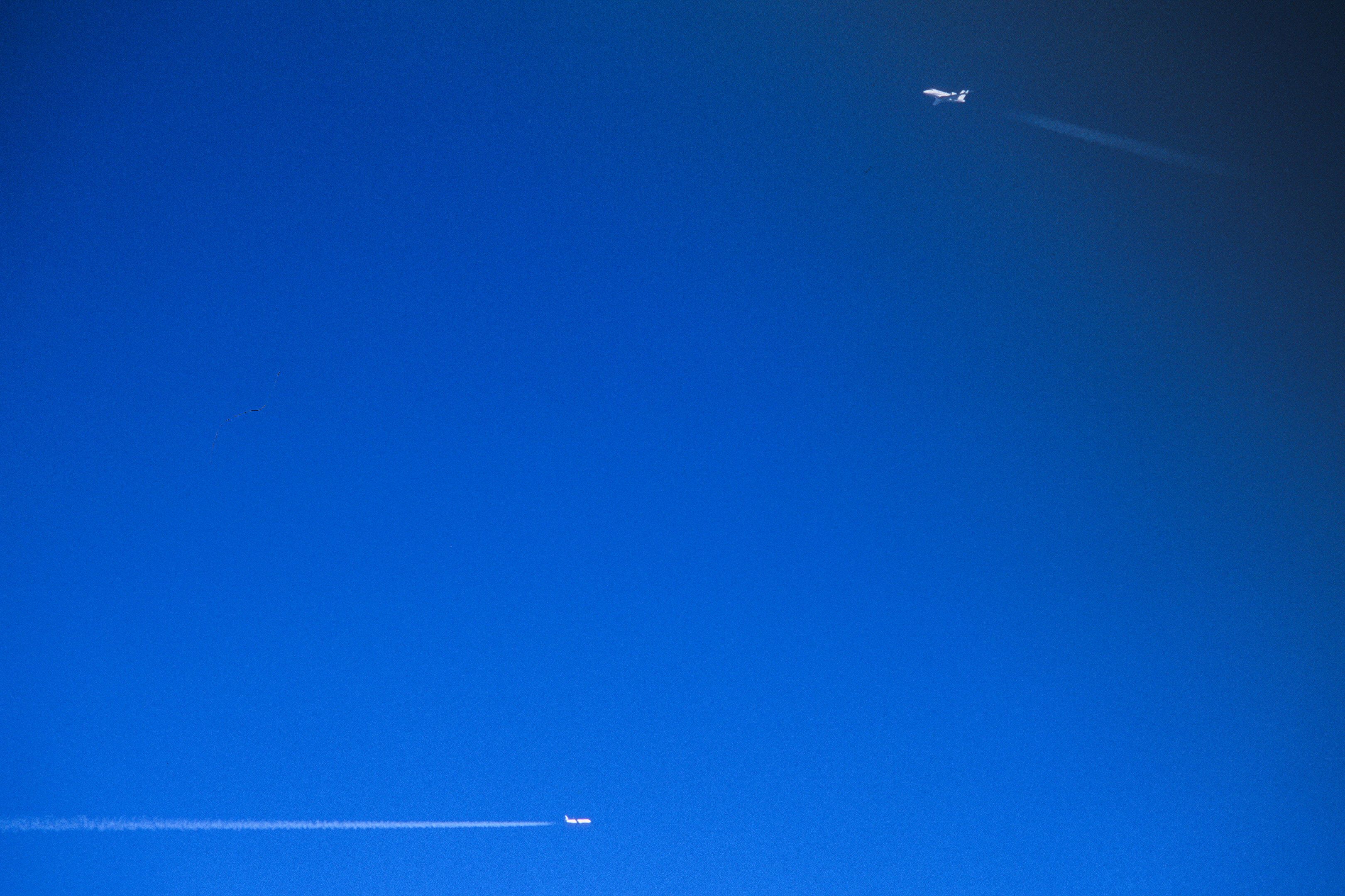 Two airplanes crossing in the blue sky