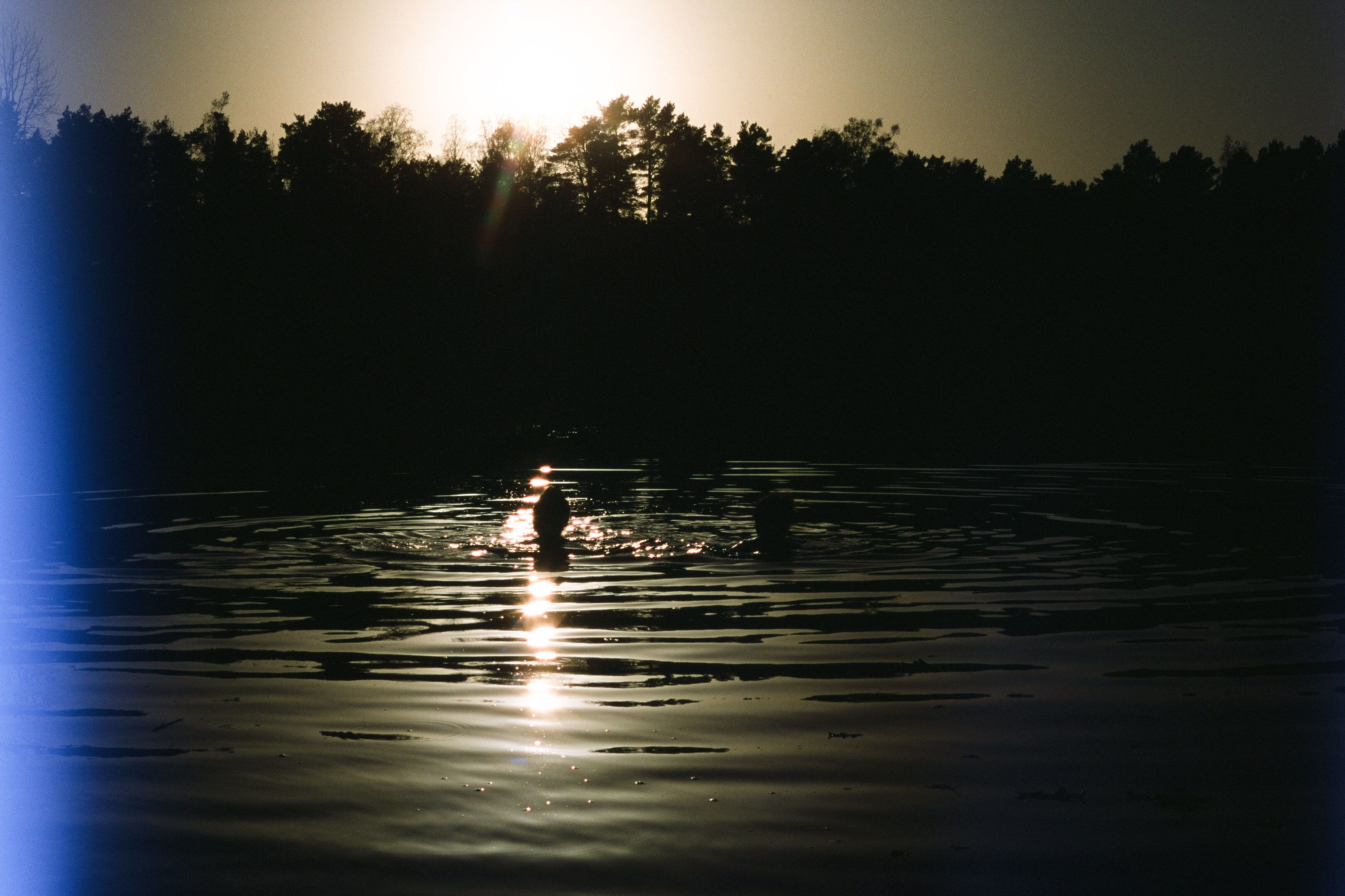 two women swimming in a lake during sunset